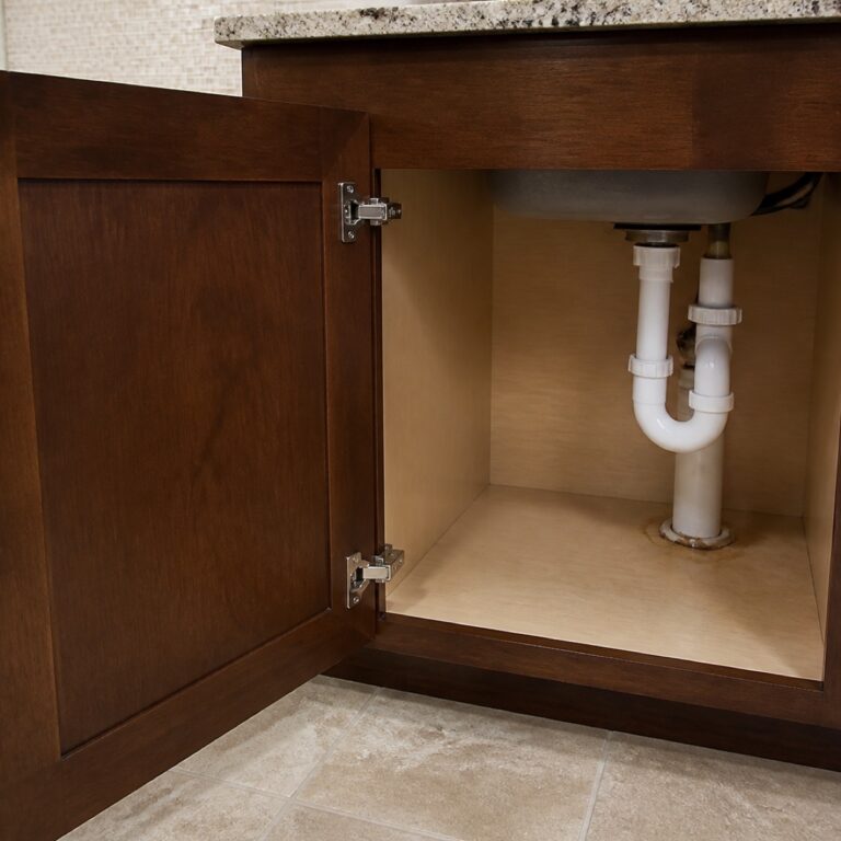 Open sink-base kitchen cabinet showing plumbing and cabinet interior for a guide to water damage after a leak